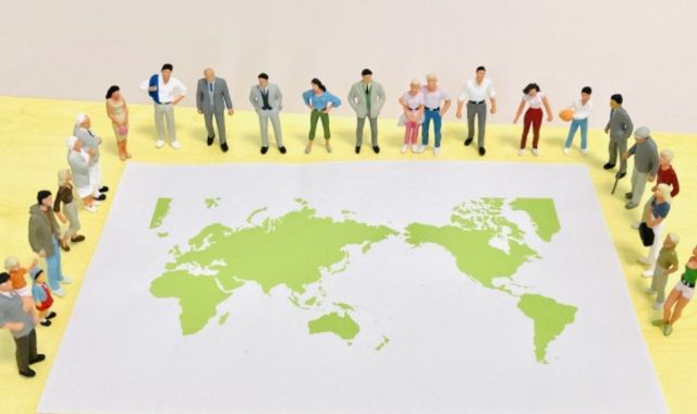 世界地図の周りに様々な国籍の人々