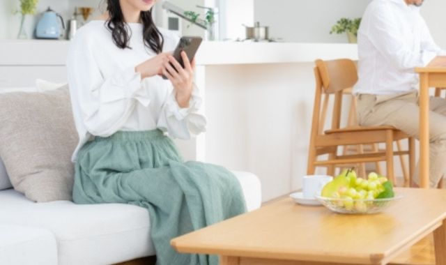 スマホを見る妻と食卓に着く夫